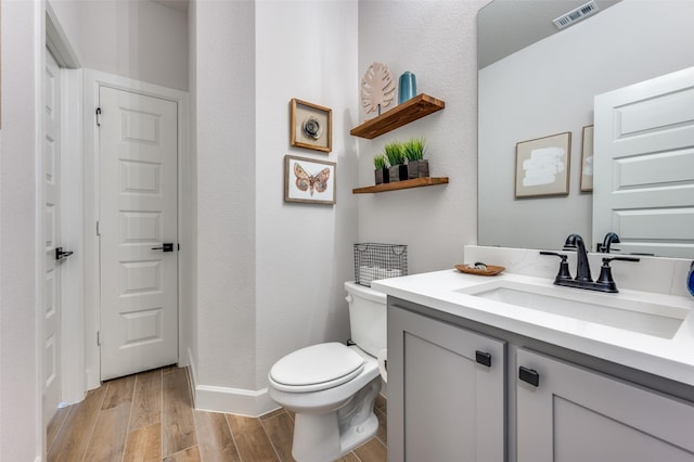 bathroom with visible vents, wood finished floors, vanity, baseboards, and toilet