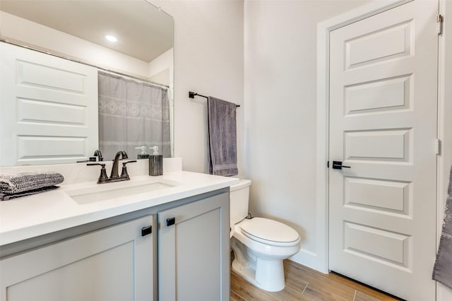 bathroom featuring toilet, a shower with curtain, wood finished floors, and vanity