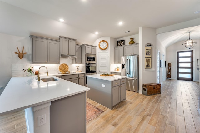 kitchen featuring stainless steel appliances, gray cabinets, a sink, and lofted ceiling