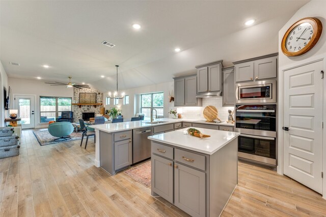 kitchen featuring gray cabinets, visible vents, appliances with stainless steel finishes, a fireplace, and a sink