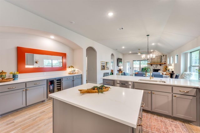 kitchen with a center island, a sink, beverage cooler, and gray cabinetry