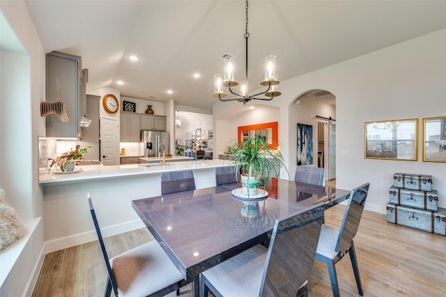 dining area with recessed lighting, a barn door, arched walkways, light wood-style flooring, and a notable chandelier