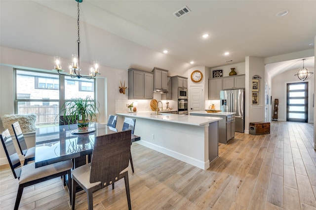 kitchen featuring appliances with stainless steel finishes, gray cabinets, and a chandelier