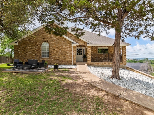 ranch-style home with brick siding, an outdoor hangout area, roof with shingles, and a front lawn