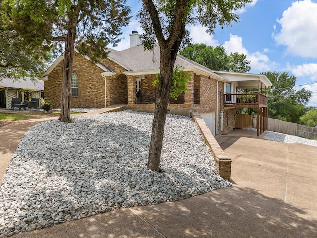 view of front of home with fence, brick siding, a garage, a chimney, and driveway