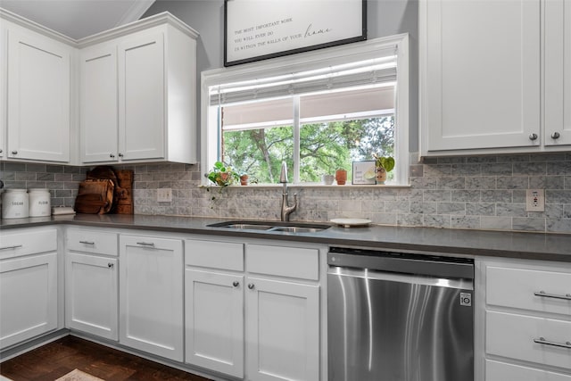 kitchen with stainless steel dishwasher, dark countertops, a sink, and tasteful backsplash