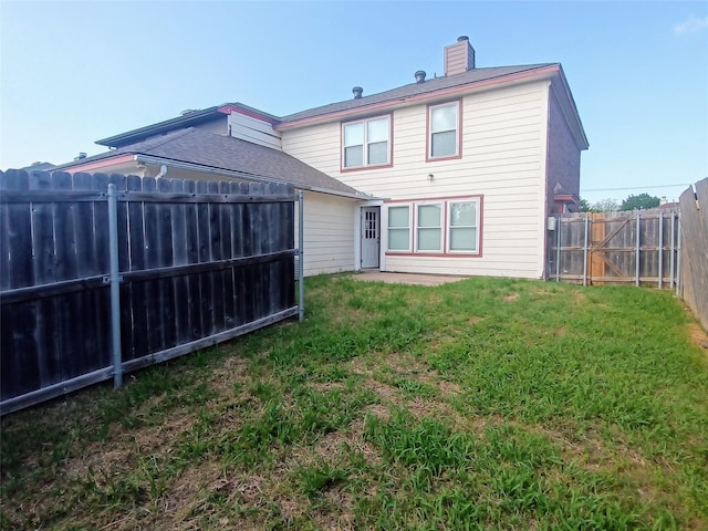 rear view of house featuring a fenced backyard, a chimney, and a lawn