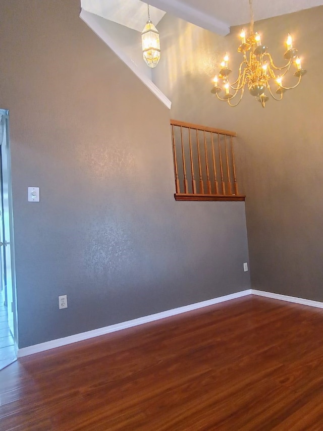 spare room with baseboards, wood finished floors, and a chandelier