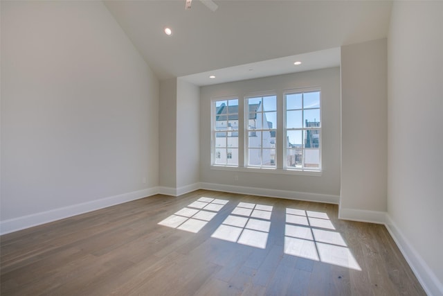 empty room featuring recessed lighting, baseboards, wood finished floors, and lofted ceiling