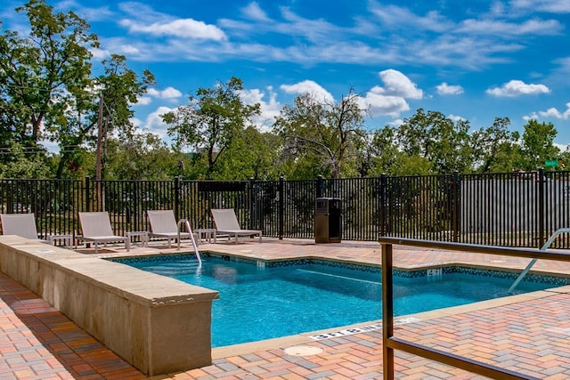 community pool with a patio and fence