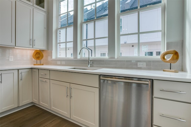 kitchen with light countertops, tasteful backsplash, a sink, and dishwasher