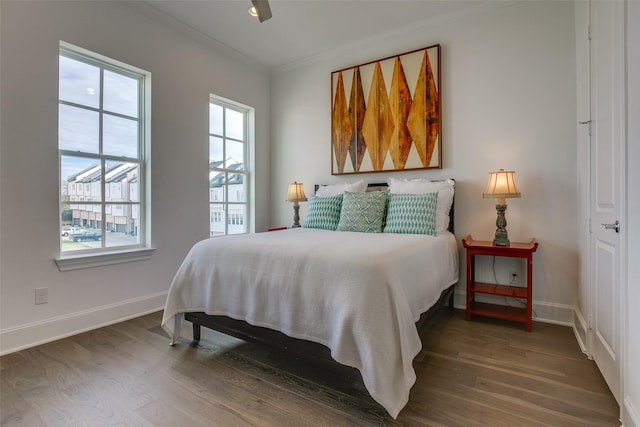 bedroom featuring ornamental molding, wood finished floors, and multiple windows