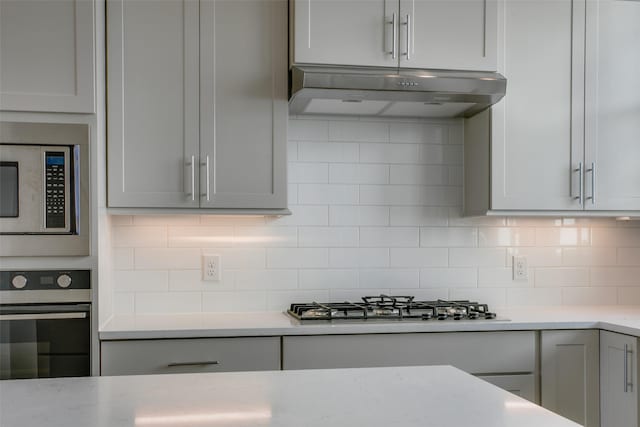 kitchen with backsplash, stainless steel appliances, and under cabinet range hood