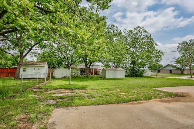 view of yard featuring a storage shed, an outbuilding, and fence private yard