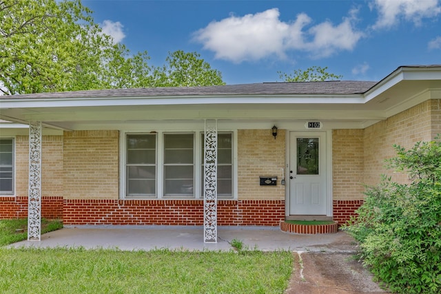 entrance to property featuring a porch and brick siding