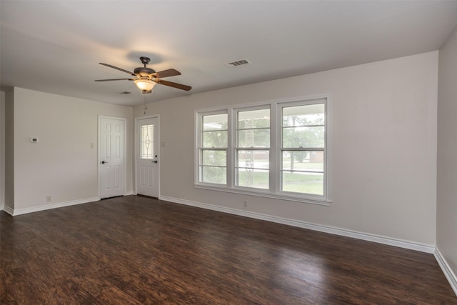 interior space featuring baseboards, a ceiling fan, dark wood-style floors, and visible vents