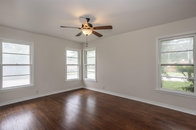 spare room featuring baseboards, a ceiling fan, and dark wood-type flooring