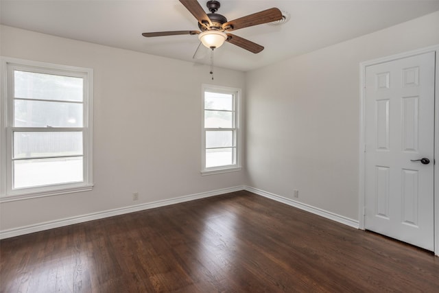 spare room with baseboards, dark wood finished floors, and ceiling fan