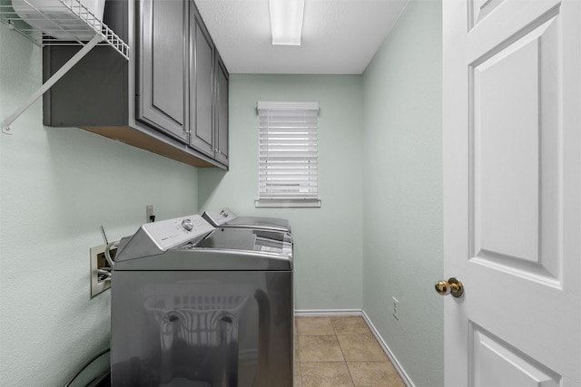 clothes washing area featuring baseboards, cabinet space, light tile patterned floors, and washing machine and clothes dryer