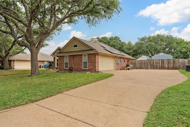 view of front of house featuring fence, an attached garage, brick siding, roof mounted solar panels, and driveway