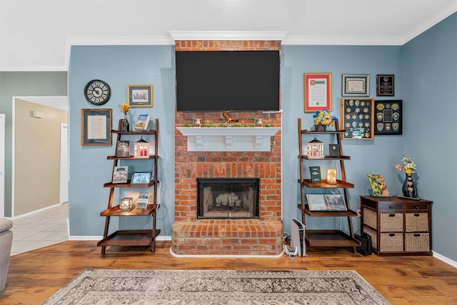 living area with a brick fireplace, baseboards, ornamental molding, and wood finished floors