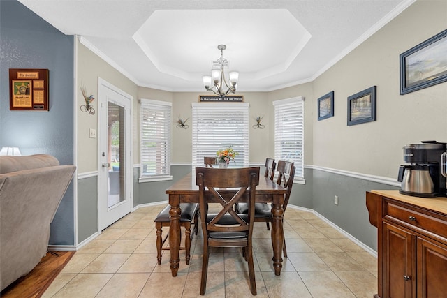 dining room with an inviting chandelier, ornamental molding, a raised ceiling, and light tile patterned flooring