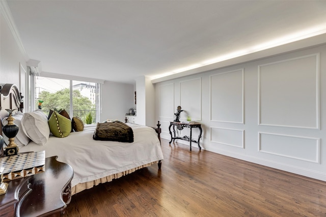bedroom with crown molding, dark wood-type flooring, and a decorative wall