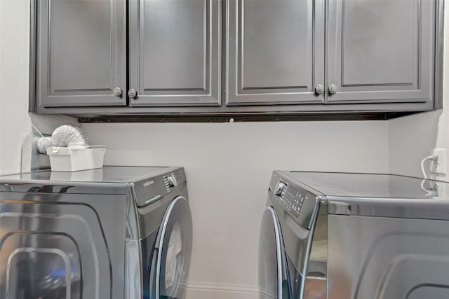 clothes washing area with separate washer and dryer and cabinet space