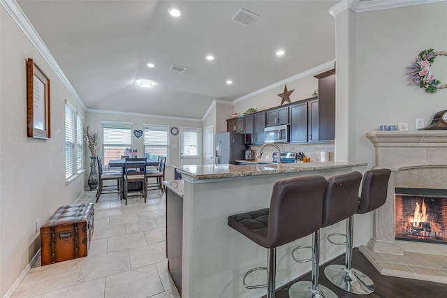 kitchen featuring visible vents, crown molding, a breakfast bar, light stone counters, and appliances with stainless steel finishes