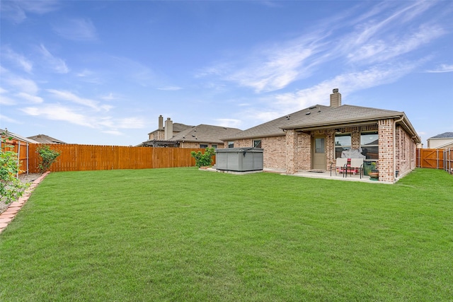 back of property featuring a fenced backyard, a chimney, brick siding, a patio area, and a lawn