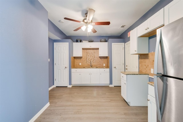 kitchen with ceiling fan, backsplash, visible vents, a sink, and freestanding refrigerator
