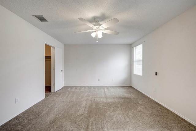 carpeted empty room with visible vents, a ceiling fan, a textured ceiling, and baseboards