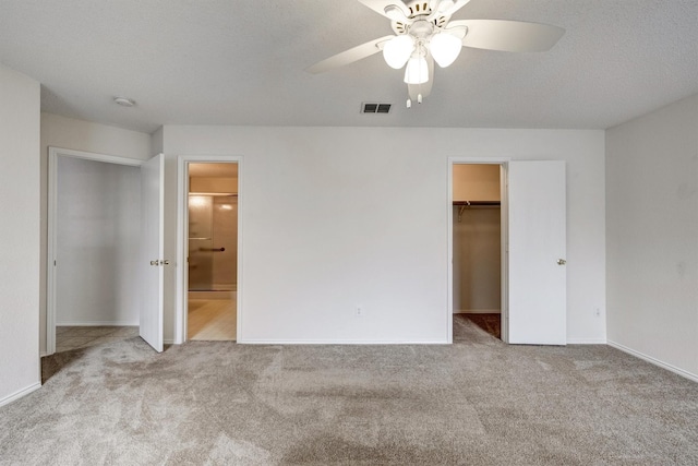 unfurnished bedroom with visible vents, baseboards, ensuite bathroom, a spacious closet, and carpet flooring