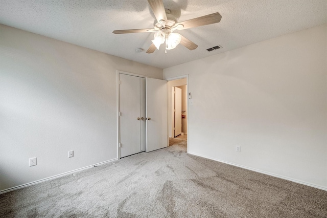 unfurnished bedroom featuring a textured ceiling, carpet, a ceiling fan, baseboards, and visible vents