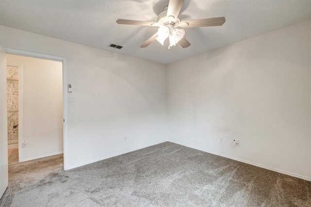spare room featuring ceiling fan, a textured ceiling, carpet, baseboards, and visible vents
