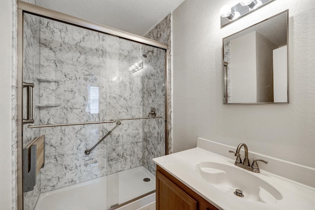 bathroom with a textured ceiling, a marble finish shower, and vanity