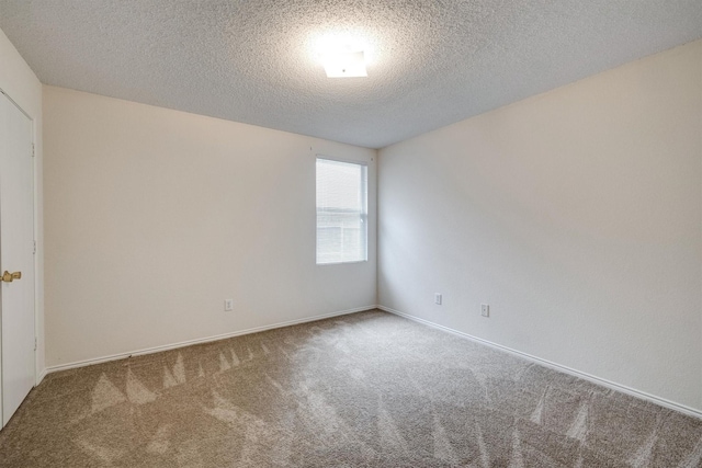carpeted empty room featuring a textured ceiling and baseboards