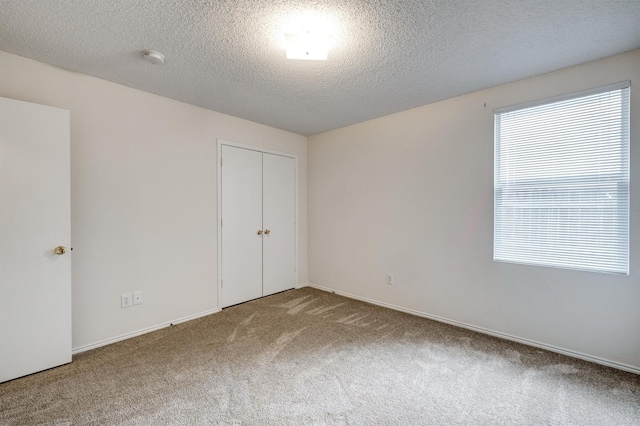 spare room featuring baseboards, carpet, and a textured ceiling