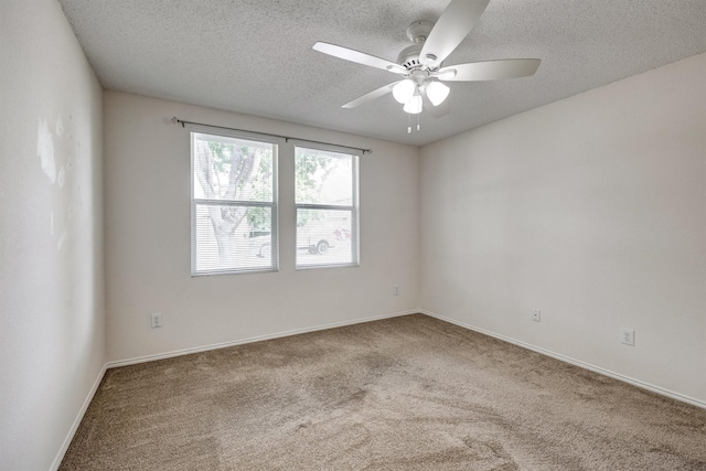 carpeted spare room featuring baseboards, a ceiling fan, and a textured ceiling