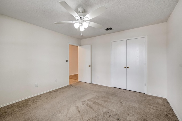 unfurnished bedroom featuring carpet flooring, a ceiling fan, a textured ceiling, and visible vents