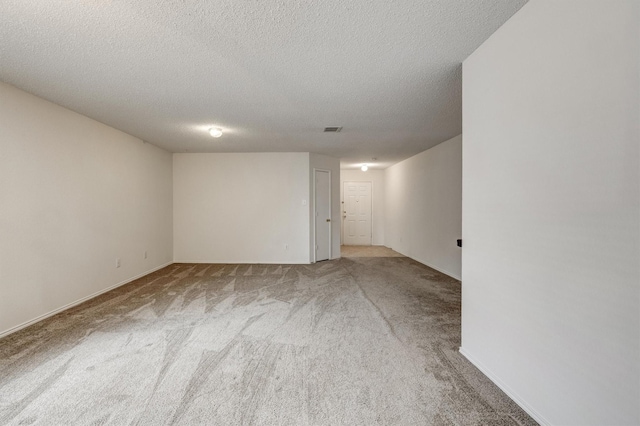 carpeted spare room featuring visible vents, a textured ceiling, and baseboards