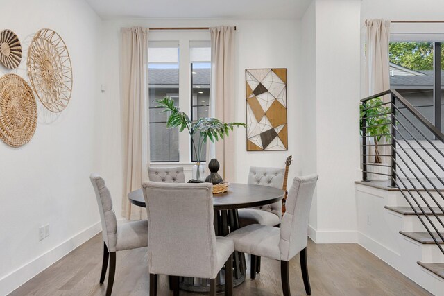 dining room with stairs, baseboards, and wood finished floors