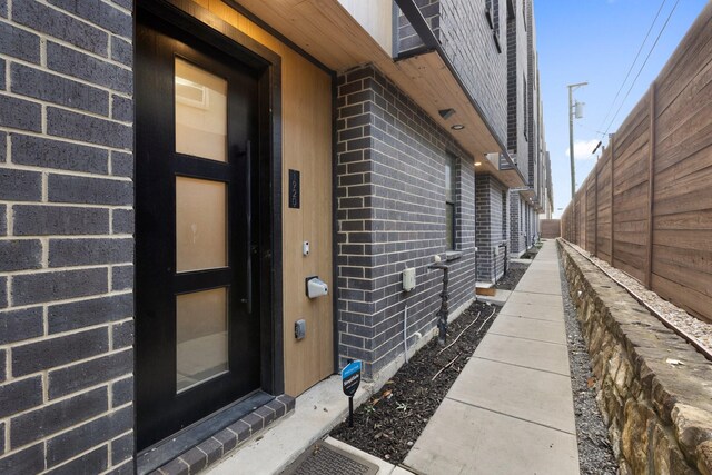 property entrance featuring brick siding and fence