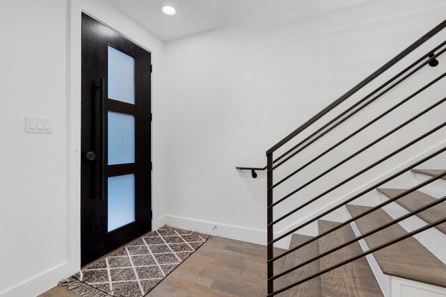 foyer entrance with stairway, baseboards, and wood finished floors