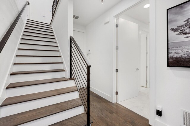 stairway featuring baseboards, visible vents, and wood finished floors