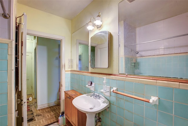 bathroom with a sink, a wainscoted wall, and tile walls