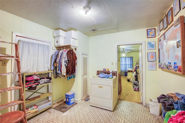 interior space featuring laundry area, a textured ceiling, washer / clothes dryer, a ceiling fan, and visible vents