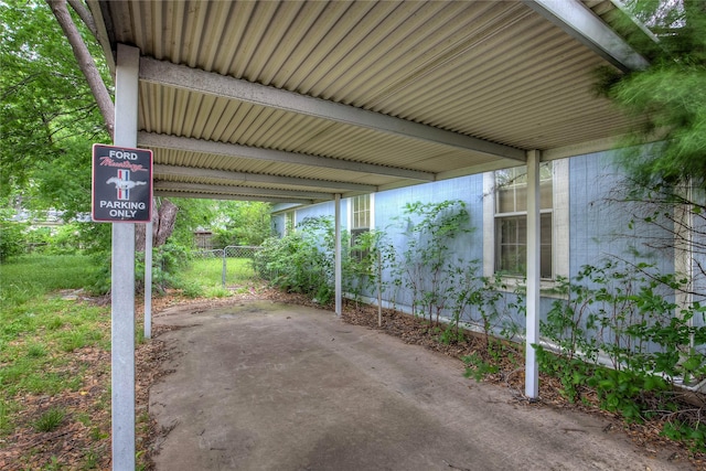 view of vehicle parking with fence and a carport
