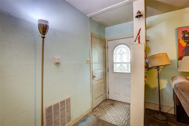 entrance foyer with visible vents, baseboards, and brick floor