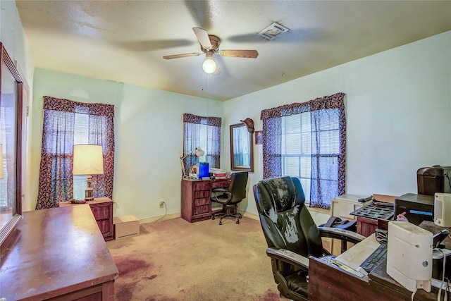 carpeted home office with baseboards, a ceiling fan, and visible vents